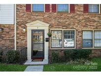 Charming brick townhome with red shutters, well-maintained landscaping, and inviting front entrance at 6322 Old Pineville Rd # E, Charlotte, NC 28217