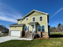 Two story home with a green exterior, stone accents, two car garage, and front porch at 1022 Heath Helms Rd, Monroe, NC 28110