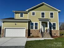 Two story home with a green exterior, stone accents, two car garage, and front porch at 1022 Heath Helms Rd, Monroe, NC 28110
