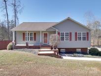 Charming single-story home featuring red shutters, inviting front porch, and well-maintained landscaping at 115 Scotch Irish Ln, Troutman, NC 28166