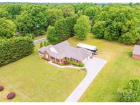 Expansive brick home with long driveway, large RV, well-maintained lawn, and lush tree cover at 119 Era St, Troutman, NC 28166