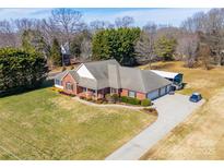 Stunning aerial view of a brick home with a large yard, long driveway, and an outbuilding at 119 Era St, Troutman, NC 28166
