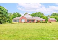 Lovely brick home boasts a sprawling lawn, manicured landscaping, and charming curb appeal at 119 Era St, Troutman, NC 28166