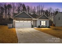 Charming home featuring a stone and vinyl exterior, two-car garage, and well-manicured lawn at 127 Tradesmen Trl, Troutman, NC 28166