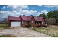 Charming home showcasing a red metal roof, wood siding, covered porch and an attached two-car garage at 3427 Joe Johnson Rd, Catawba, NC 28609