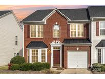 Charming brick two-story townhome with red shutters, black roof and an attached white one-car garage at 3822 Carl Parmer Dr, Harrisburg, NC 28075