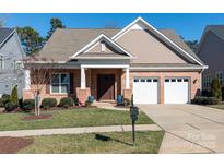 Charming brick home featuring an attached two-car garage, manicured lawn, and covered front porch at 14310 Cameryn Elise Dr, Cornelius, NC 28031