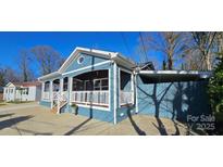 Charming blue home with a covered porch, white railings, and a well-manicured front yard at 2721 Dora Dr, Charlotte, NC 28215