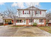 Charming two-story home featuring a large driveway, covered parking, and red brick and siding accents at 623 Spring Sw St, Concord, NC 28025