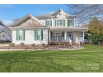 Charming two-story home boasts green shutters, a well-manicured lawn and inviting front porch at 11130 Mccamie Hill Pl, Concord, NC 28025