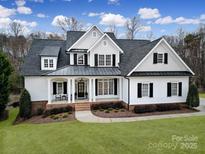 Beautiful two-story home boasts a manicured lawn and a welcoming front porch with classic black shutters and white trim at 411 Belo Ct, Fort Mill, SC 29715