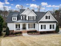 Beautiful two-story home featuring a black metal roof, white siding, and manicured landscaping at 411 Belo Ct, Fort Mill, SC 29715