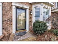Inviting front door of a brick home with decorative door surround, transom, and meticulously maintained landscaping at 5472 Ives Nw St, Concord, NC 28027