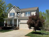 Charming two-story home with well-manicured lawn, attached garage, and a welcoming front porch at 114 Tomahawk Dr, Mooresville, NC 28117