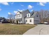 Beautiful white farmhouse with a well-manicured lawn and inviting curb appeal on a sunny day at 8788 Potter Rd, Matthews, NC 28104