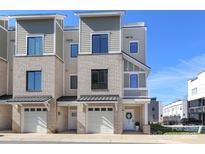 A modern townhome featuring a two-car garage, brick accents, and a welcoming front entrance at 932 Cityscape Dr, Charlotte, NC 28205