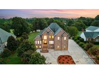 Majestic brick home with a grand entrance, manicured landscaping, and ample parking at twilight at 109 Dabbling Duck Cir, Mooresville, NC 28117