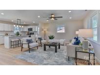 Bright living room open to a modern white kitchen with a large island and bar seating at 3617 12Th Street Ne Dr, Hickory, NC 28601