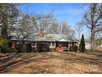 Charming brick home featuring a well-maintained front yard, red door and ample shrubbery at 7107 Wilson Grove Rd, Mint Hill, NC 28227