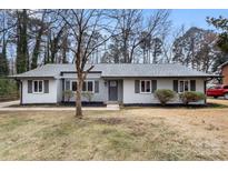 Charming single-story home with gray exterior, manicured lawn, and symmetrical shrubbery at 7124 Lake Dr, Matthews, NC 28104