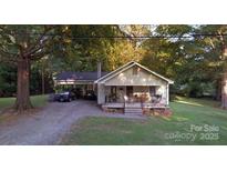 Charming single-story home with a covered carport and inviting front porch surrounded by mature trees at 1216 Innis Ave, Kannapolis, NC 28081