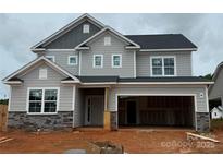 Two-story home featuring gray siding, stone accents, a two-car garage, and architectural roof details at 2216 Camber Dr # Cwo0074, Gastonia, NC 28054