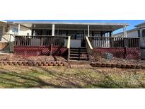Enclosed back porch with red lattice and access to a covered deck overlooking yard at 103 Dogwood Cir, New London, NC 28127