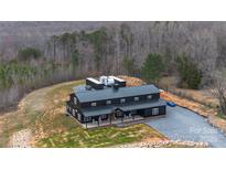 A gorgeous black two-story barndominium home featuring a metal roof, gravel driveway, and level yard at 2288 Boheler Rd, Clover, SC 29710