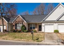 Charming brick and siding townhome with attached garage, neat landscaping, and a well-maintained lawn on a sunny day at 4642 Willow Glen Rd, Harrisburg, NC 28075