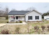 Charming single-story home featuring a cozy front porch with an American flag and a well-manicured front yard at 601 Apple St, Gastonia, NC 28054