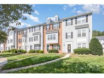 Well-maintained townhome exteriors with manicured lawns and walkways under a blue sky at 9254 Washam Potts Rd, Cornelius, NC 28031