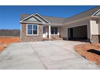 Charming single-story home featuring stone accents, a spacious driveway, and an attached garage under a clear blue sky at 2081 Fordhill St, Rock Hill, SC 29732