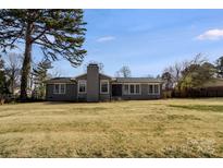Charming single story home with gray brick, chimney, large backyard and mature trees on a sunny day at 320 Paradise Cir, Belmont, NC 28012