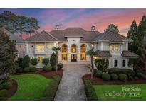 Elegant Mediterranean-style home featuring a tile roof, manicured landscaping, and a circular driveway at 18432 Harbor Light Blvd, Cornelius, NC 28031
