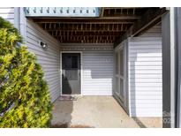 Inviting entrance with muted grey siding, concrete patio and a colorful 'welcome' doormat at 11036 Harrowfield Rd, Charlotte, NC 28226