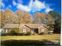 Charming single-story brick home featuring a well-manicured lawn and mature trees in a quiet neighborhood at 14818 Hooks Rd, Matthews, NC 28105