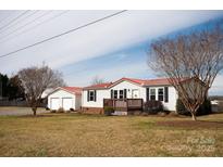 Charming single-story home with a red roof, inviting front porch, and detached garage at 3991 Bunker Hill School Rd, Claremont, NC 28610