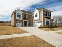 Stunning two-story home boasts a brick and siding exterior, three-car garage, and a basketball hoop on the long driveway at 611 Yucatan Dr, Waxhaw, NC 28173