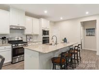 Bright kitchen with white cabinets, stainless steel appliances, and a granite island with seating at 10140 Lilac Ct, Charlotte, NC 28215