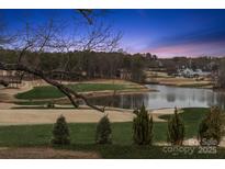 Scenic golf course view with a serene lake, complemented by a beautiful sunset backdrop and a stately home at 145 Milford Cir, Mooresville, NC 28117