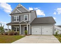 Charming two-story home featuring a two-car garage and welcoming front porch, all under a clear blue sky at 201 Bennett Trail Dr, Mount Holly, NC 28120