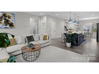 Bright living room showcasing a modern sofa, round coffee table, and open layout into the kitchen at 201 Bennett Trail Dr, Mount Holly, NC 28120