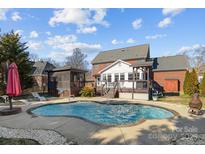 An inviting in-ground pool with a tanning ledge and a covered porch and lush landscape at 234 Falcons Rdg, Matthews, NC 28104