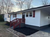 Charming single-story home with white siding, red shutters, and a covered parking area at 305 W Poplar St, Stanley, NC 28164