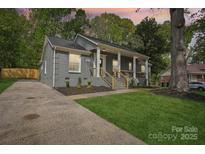 Charming grey brick home with a well-manicured lawn and inviting front porch with wooden accents at 6813 Elm Forest Dr, Charlotte, NC 28212
