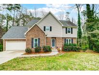 Charming two-story home with a brick facade, green lawn, and beautiful landscaping at 7921 Altacrest Dr, Concord, NC 28027
