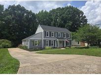 Charming two-story home with gray siding, black shutters, an American flag, and a lush green lawn at 1133 Bloom Wood Ln, Matthews, NC 28105