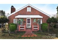 Charming brick home with a covered front porch, landscaping, and awning, offering classic curb appeal at 1650 10Th Ne Ave, Hickory, NC 28601