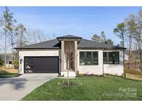 Modern home featuring a white brick facade, black trim, and a sleek, contemporary garage door at 17201 Green Hill Rd, Charlotte, NC 28278