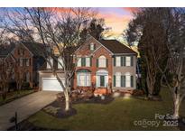 Charming two-story brick home featuring green shutters, a manicured lawn, and a two-car garage at 19715 Beneteau Ct, Cornelius, NC 28031